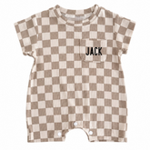 A short-sleeve baby romper with a brown and cream checkerboard pattern, featuring a chest pocket with the name &