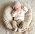 A sleeping newborn baby wearing a cream knit onesie with &