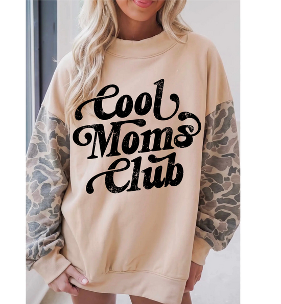 A woman wearing a beige crewneck sweatshirt with &