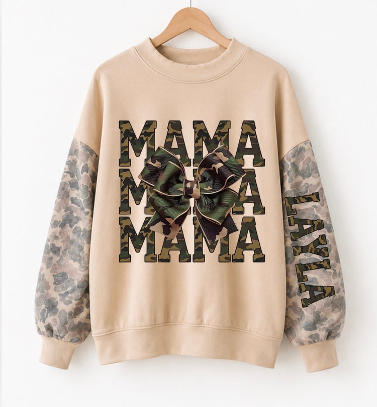 A beige crewneck sweatshirt hanging on a wooden hanger against a white background. The sweatshirt features &